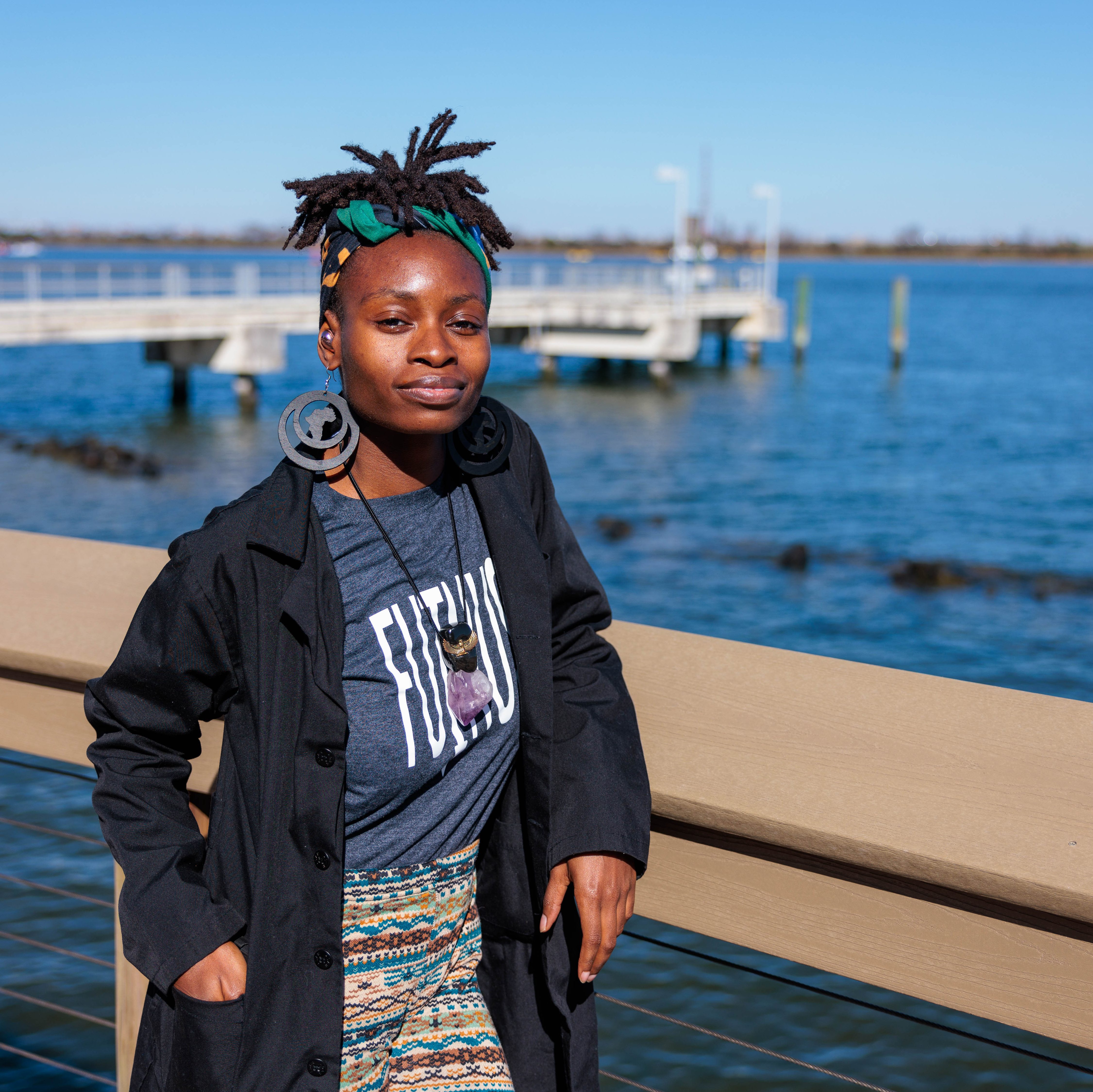 Cultural activist, Akua Page, poses in front of the inlet with a view of a dock.
