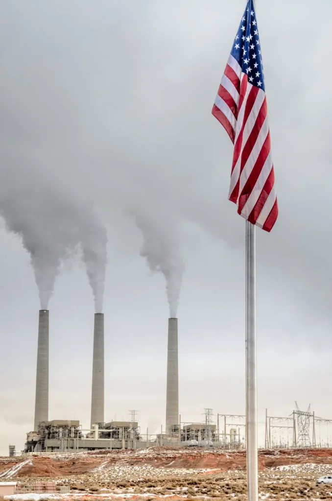 Smoke stacks in background. American flag in foreground.