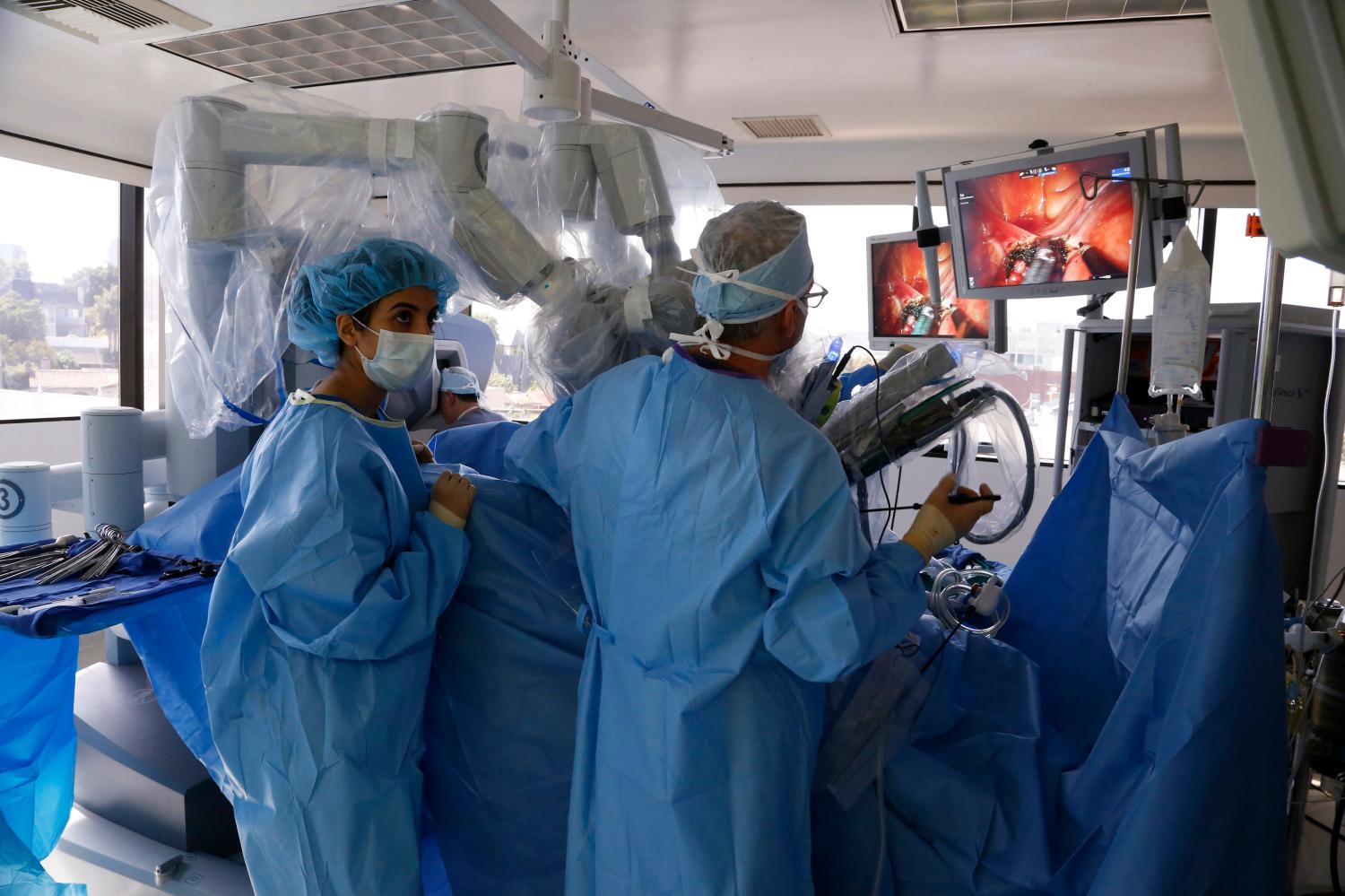 Reuters/Lucy Nicholson - Doctors David Ghozland (2nd L, rear, operating robotic arms from computer) and Marc Winter (R) perform a single-site robotic-assisted hysterectomy at miVIP Surgery Center, in Los Angeles, California April 23, 2014