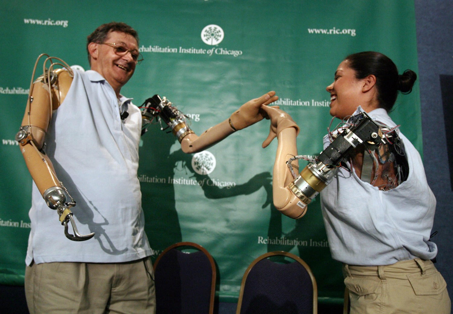 Claudia Mitchell (R), the first woman to receive a bionic arm, uses her new prosthetic arm to "high five" with the first bionic arm recipient Jesse Sullivan at a news conference in Washington September 14, 2006. REUTERS/Jason Reed