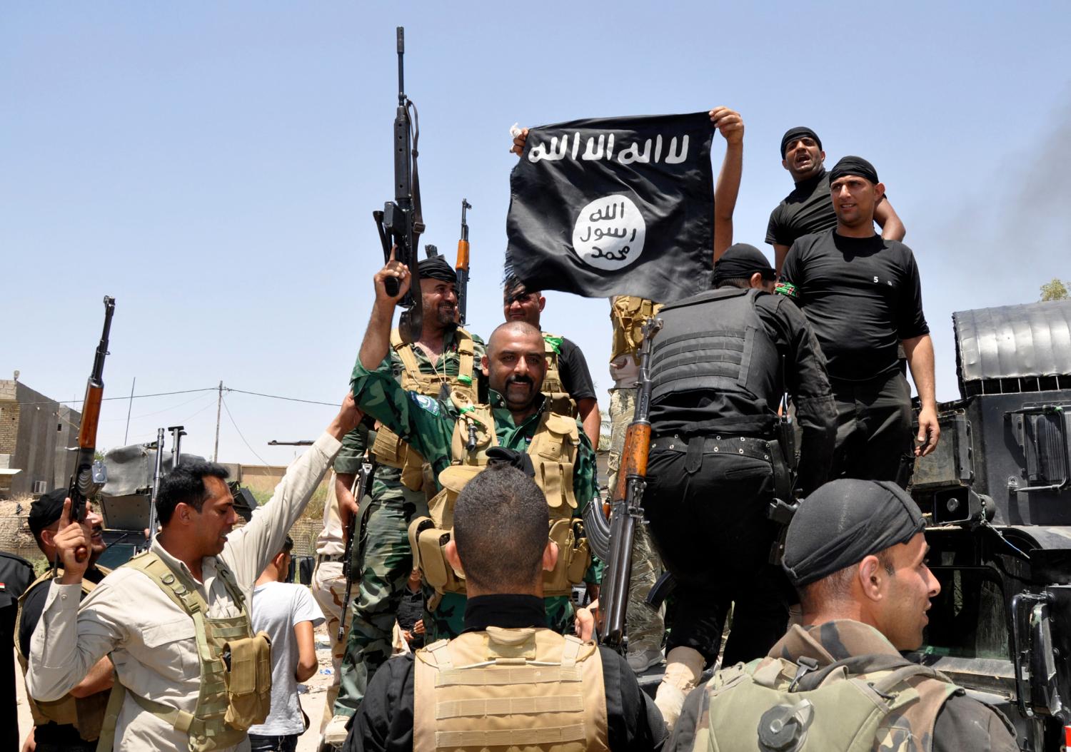 Reuters - Iraqi security forces pull down a flag belonging to Sunni militant group Islamic State of Iraq and the Levant (ISIL) during a patrol in the town of Dalli Abbas in Diyala province, June 30, 2014.