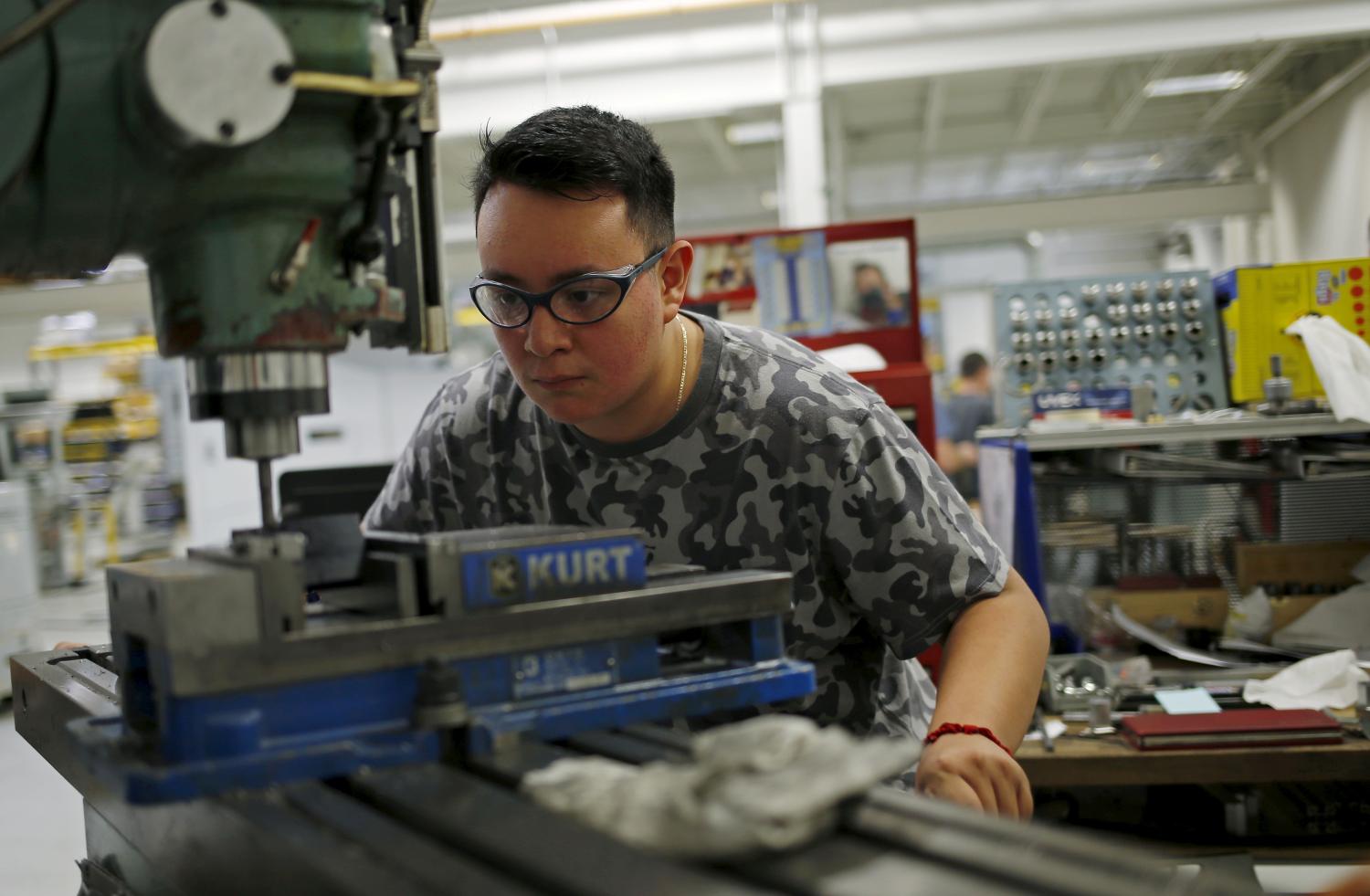 A student operates a drill press in a metalwork class