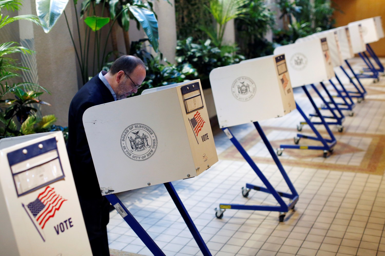 A man votes at a small, desk-style voting booth.