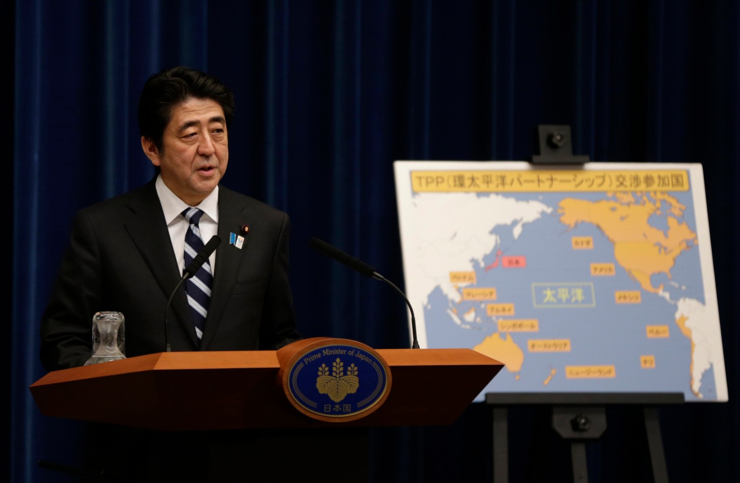 Japan's Prime Minister Shinzo Abe speaks next to a map showing participating countries in rule-making negotiations for the Trans-Pacific Partnership (TPP) during a news conference at his official residence in Tokyo March 15, 2013. Abe announced on Friday that Tokyo will seek to join talks on a U.S.-led Pacific free trade pact which proponents say will tap vibrant regional growth, open Japan to tough competition and boost momentum for reforms needed to revive the long-stagnant economy. REUTERS/Toru Hanai
