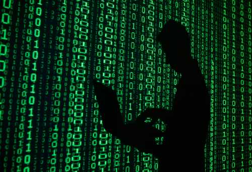 Person with laptop standing in front of screen with computer code.