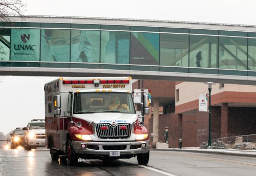 An ambulance drives under a pedestrian bridge
