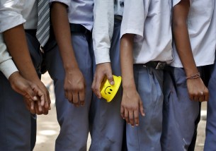 A student holds his tiffin box while standing in a queue to receive free mid-day meal being distributed by municipal workers at a government school in New Delhi, India, May 6, 2015.