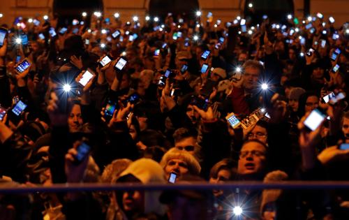Protesters raise their smartphones with screens lit