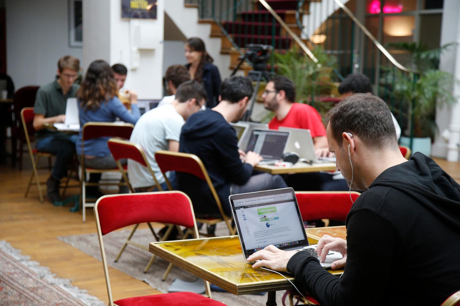 A group of workers at a technology startup work on their laptops