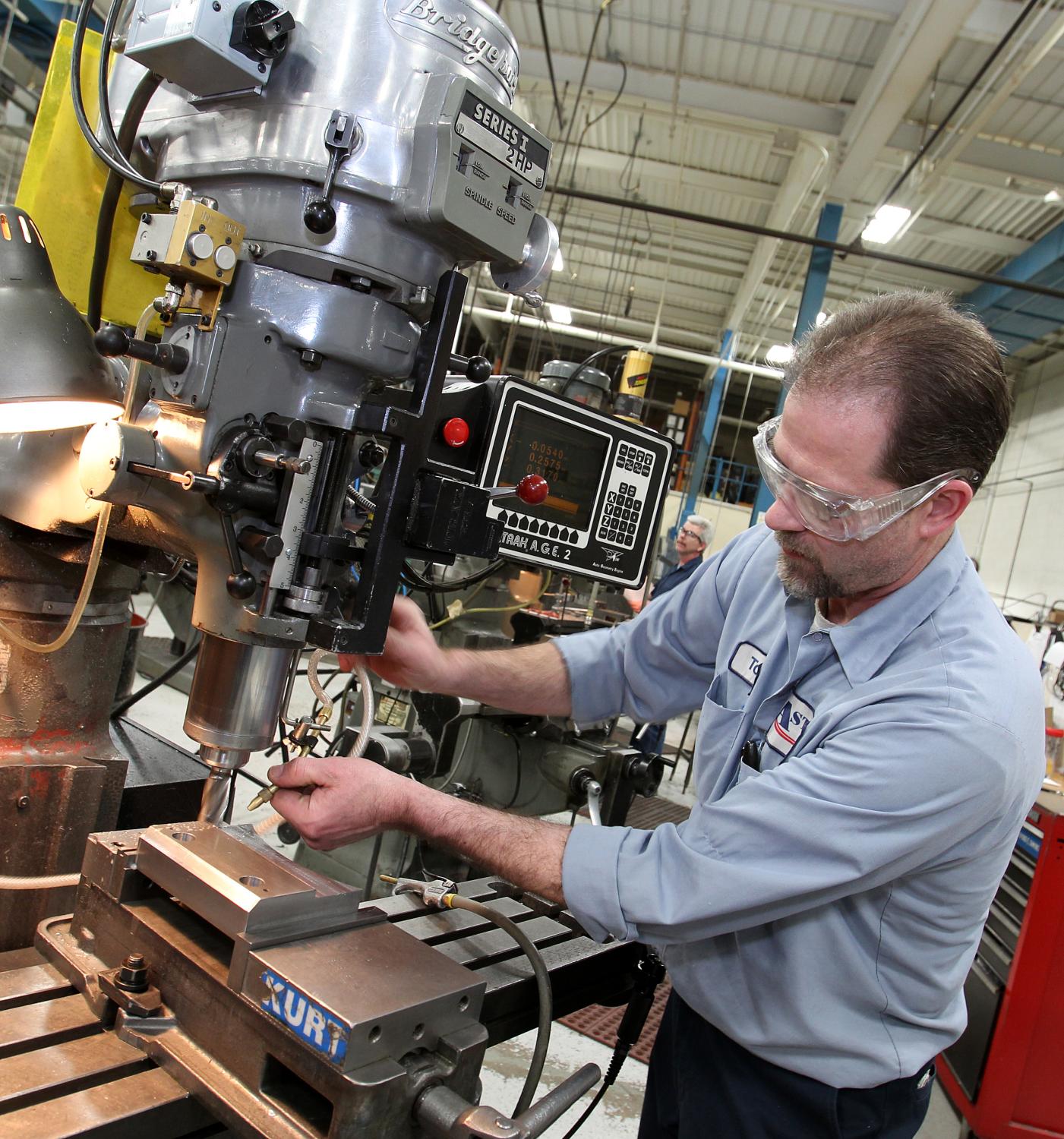 A man stands at a factory putting things together.