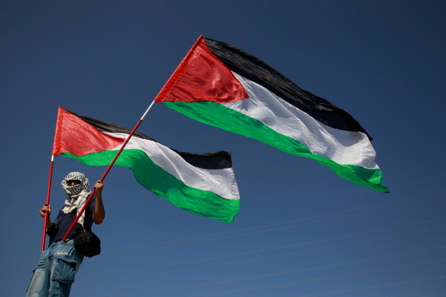 An Israeli Arab holds Palestinian flags during a demonstration calling for the right of return for refugees who fled the war which followed Israel's independence, on the anniversary of the creation of the state in the town of Abu Sinan, northern Israel, April 26, 2012. REUTERS/Ammar Awad (ISRAEL - Tags: POLITICS CIVIL UNREST)