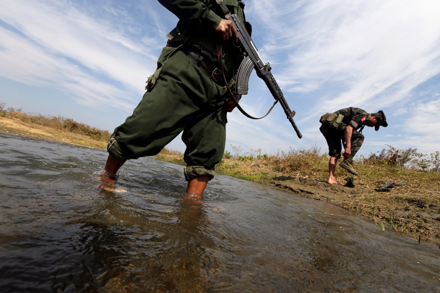 A soldier from the Kachin Independence Army (KIA) puts on his shoes as he and his comrade cross a stream towards the front line in Laiza, Kachin state, January 29, 2013. Myanmar's government started talks with top commanders of the KIA rebel group in China on February 4, 2013 to try to rescue a faltering peace process and end one of the country's bloodiest ethnic conflicts. KIA is fighting for autonomy for Kachin state within a federal Myanmar, which successive governments of the ethnically diverse country have long rejected. Picture taken January 29, 2013. REUTERS/David Johnson