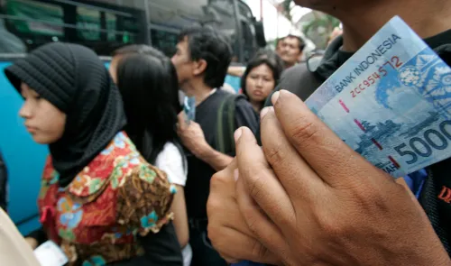 People queue to exchange new bank notes at a mobile bank services in Jakarta