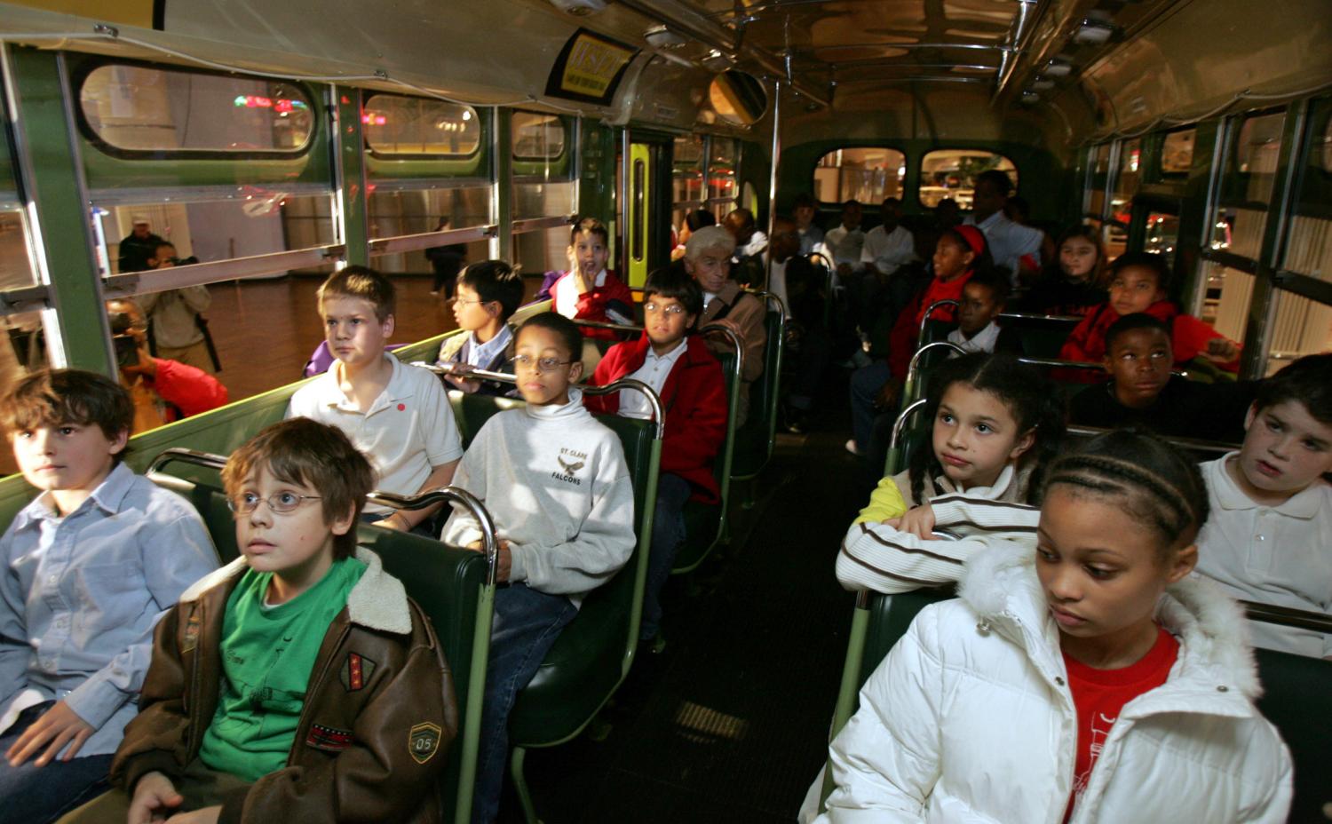 A multi-racial group of students sit next to each other on the actual bu