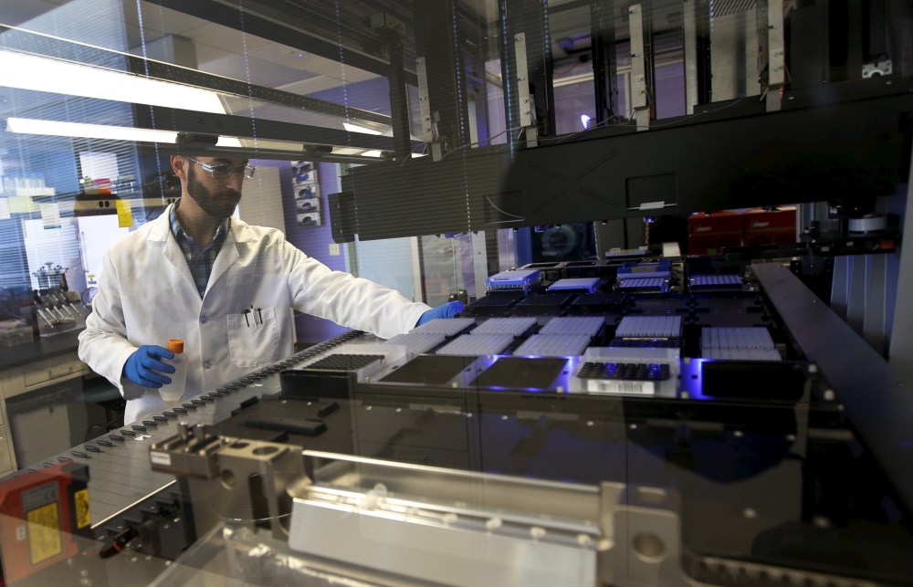 Technician Matthew Smith loads a robotic DNA sample automation machine