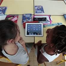 Elementary school children share an electronic tablet on the first day of class in the new school year in Nice, September 3, 2013.