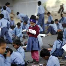 A schoolgirl reads from a textbook at an open-air school in New Delhi November 20, 2014.