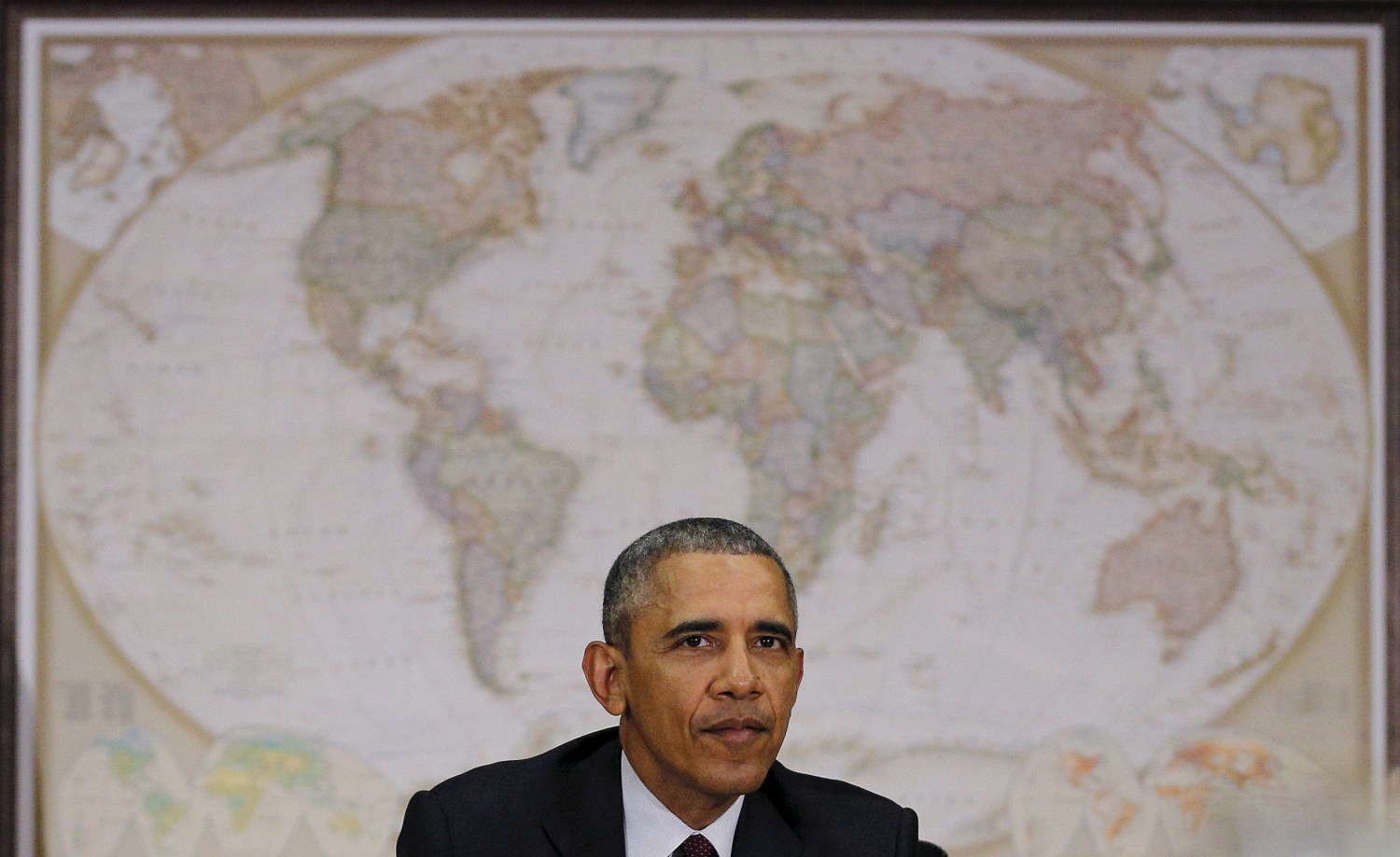 President Barack Obama sitting in front of a map of the world