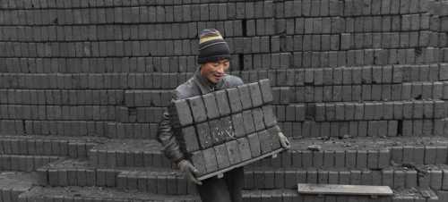 A labourer carries honeycomb briquettes at a coal processing factory in Shenyang, Liaoning province. REUTERS/Sheng Li/