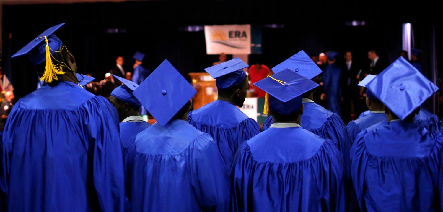 Inmates stand to receive their GED at a high school graduation ceremony