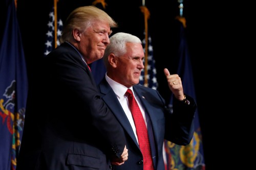 Mike Pence and Donald Trump shake hands, smiling, as Pence gives a thumbs-up.