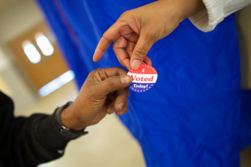 REUTERS/Mark Makela - Voting machine operator Robin Coffee-Ruff hands a sticker to a voter who cast his ballot.