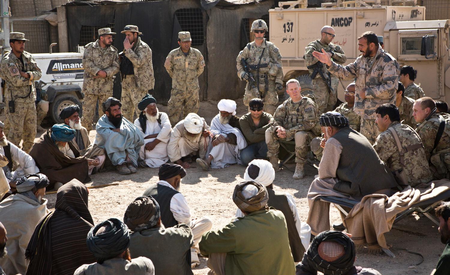 Afghans listen to a speaker at a shura - a meeting between village elders, U.S. troops and Afghan National Security Forces - near Command Outpost AJK (short for Azim-Jan-Kariz, a near-by village) in Maiwand District, Kandahar Province, Afghanistan, January 26, 2013. REUTERS/Andrew Burton (AFGHANISTAN - Tags: POLITICS MILITARY) - RTR3CZMS