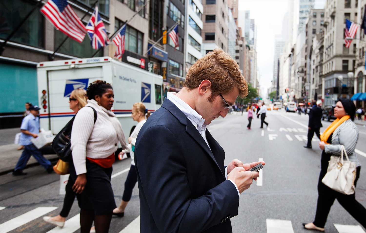 A man uses his Apple iPhone while walking across 5th Avenue in New York.