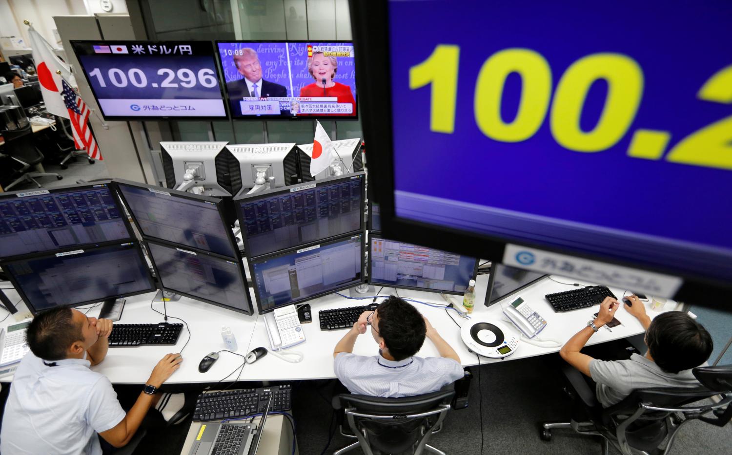 Employees of a foreign exchange trading company work near monitors displaying first U.S. presidential debate between U.S. Republican nominee Donald Trump and Democratic presidential nominee Hillary Clinton (REUTERS/Toru Hanai)