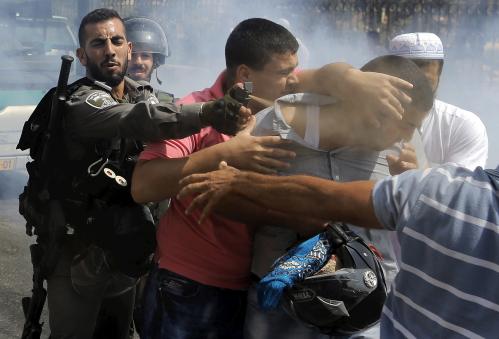 Israeli border policeman uses pepper spray on a Palestinian man during clashes near Arab East Jerusalem