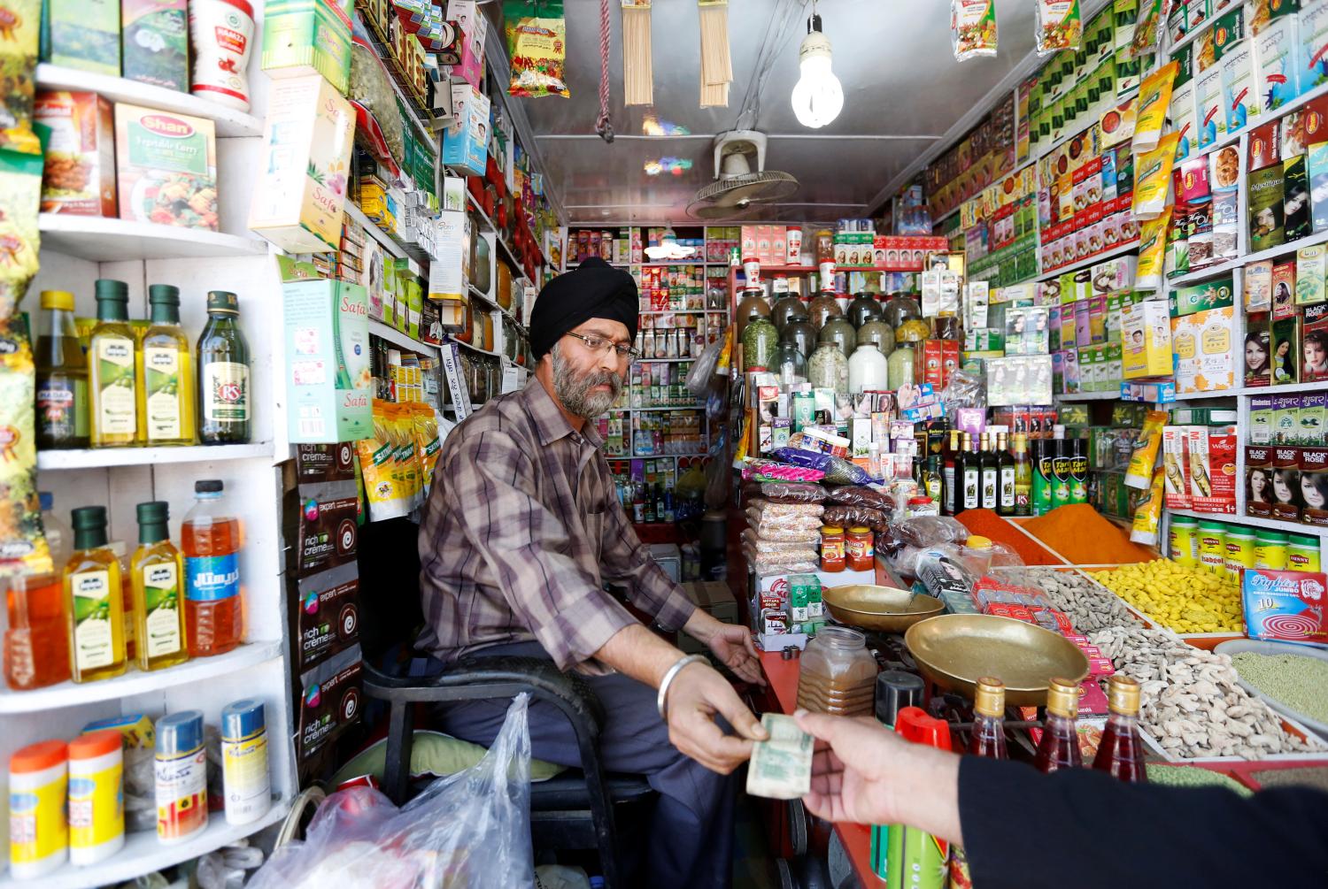 Afghan Sikh Jagtar Singh Laghmani, 50, accepts money from a customer at his traditional herb shop in Kabul, Afghanistan June 19, 2016.