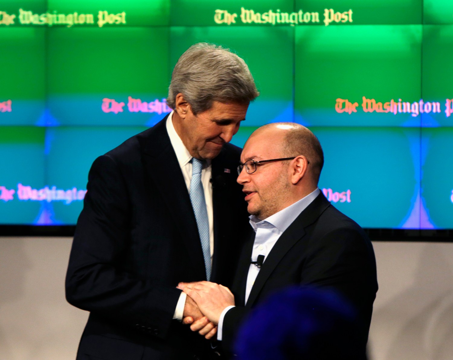 Washington Post reporter Jason Rezaian (R) is greeted by U.S. Secretary of State John Kerry at the grand opening of the Washington Post newsroom in Washington January 28, 2016. Rezaian was recently released from 18 months of captivity in Iran. REUTERS/Gary Cameron - RTX24FQ1
