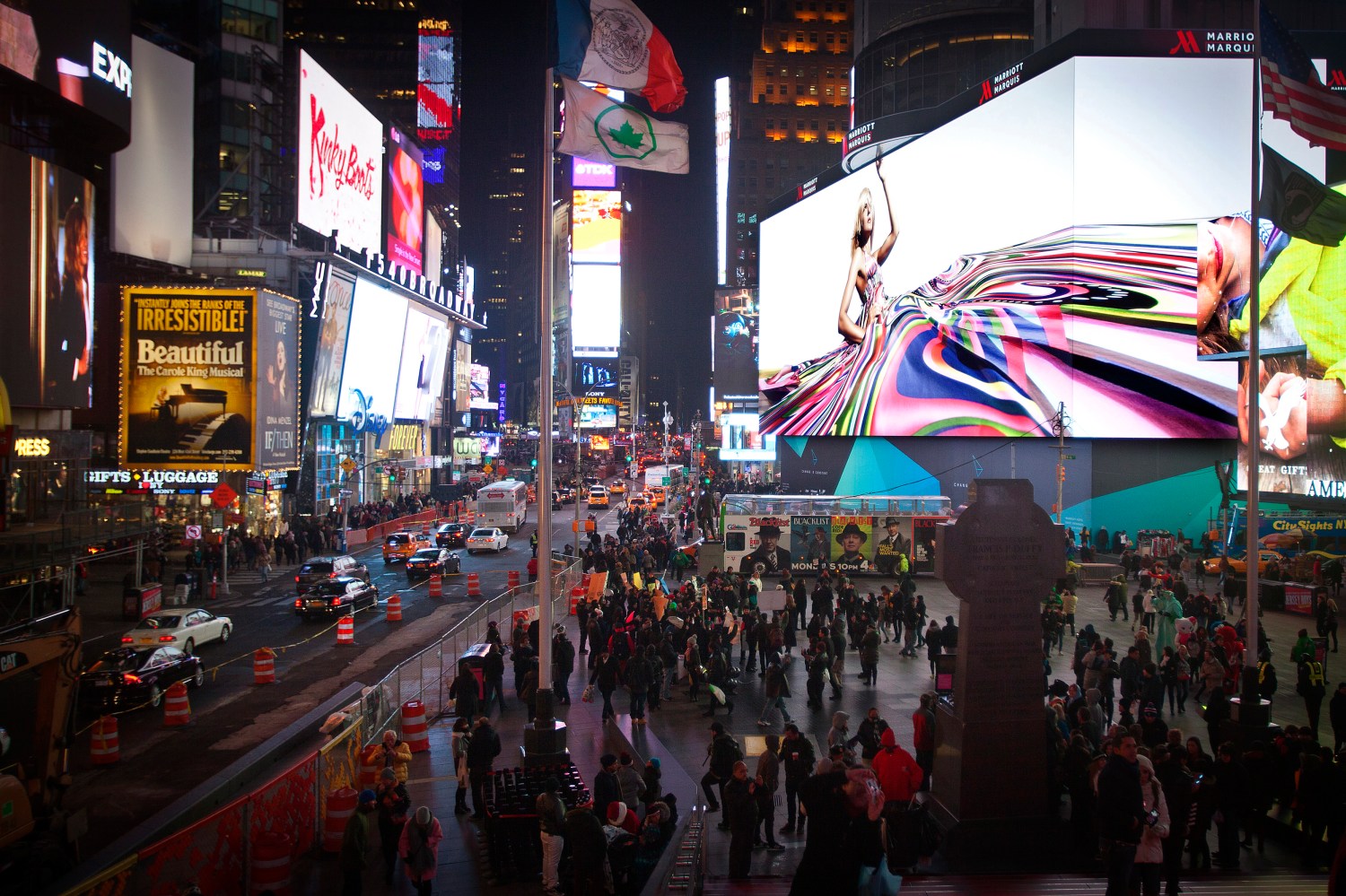 People walk underneath a giant new advertising screen in Times Square, New York, November 20, 2014. The biggest advertising billboard in Times Square history, longer that a football field and eight stories high, which is the world's largest high-definition video display with nearly 24 million LED pixels, lit up for the first time on Tuesday. The rate for a four-week advertising blitz is $2.5 million, according to the New York Times.