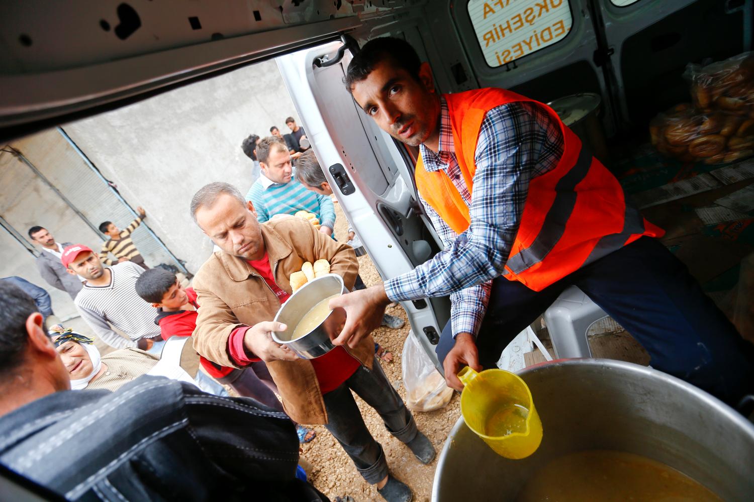 A Turkish aid worker distributes food to Kurdish refugees from the Syrian town of Kobani in a camp in the southeastern town of Suruc, Sanliurfa province, October 16, 2014. The United States is bombing targets in Kobani for humanitarian purposes to relieve defenders of the Syrian town and give them time to organize against Islamic State militants, a senior U.S. official said on Wednesday. REUTERS/Kai Pfaffenbach (TURKEY - Tags: MILITARY CONFLICT POLITICS) ) - RTR4ADLC