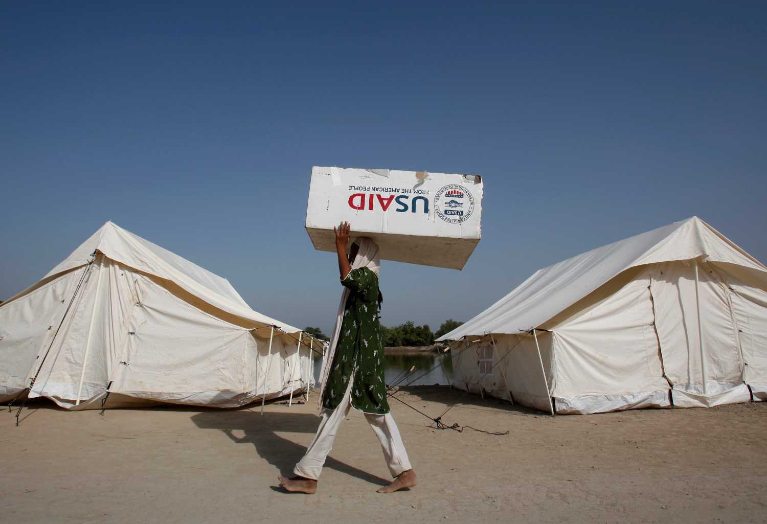 A woman, who has been displaced by floods, uses a USAID box to move her belongings while taking refuge on an embankment at Chandan Mori village in Dadu, some 320 km (199 miles) north of Karachi October 10, 2010. REUTERS/Akhtar Soomro (PAKISTAN - Tags: DISASTER ENVIRONMENT) - RTXT9RN