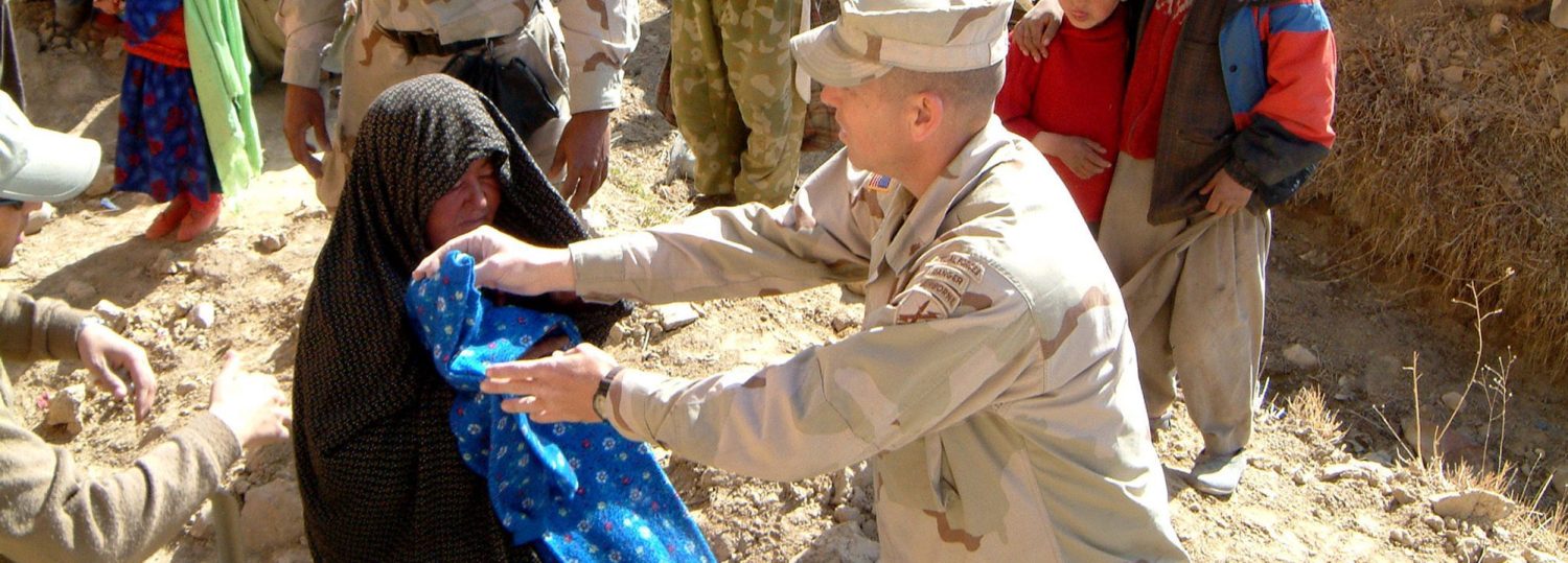 U.S. civil affairs soldier based with a Provincial Reconstruction team hand out humanitarian relief to local Afghans in Bamiyan province, Afghanistan in this picture taken March 2003. Courtesy U.S. Army/Handout via REUTERS ATTENTION EDITORS - THIS IMAGE WAS PROVIDED BY A THIRD PARTY. EDITORIAL USE ONLY - RTX2FNEA