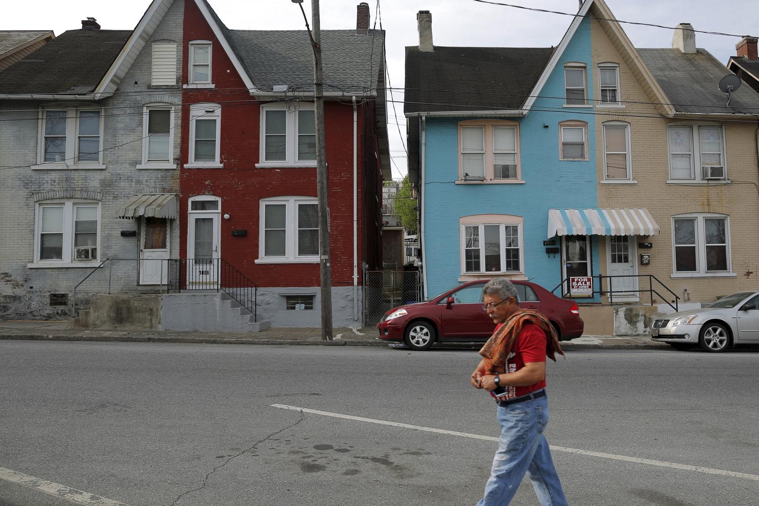 A man walks past multi-colored homes that face the now-closed Bethlehem Steel mill in Bethlehem, Pennsylvania.