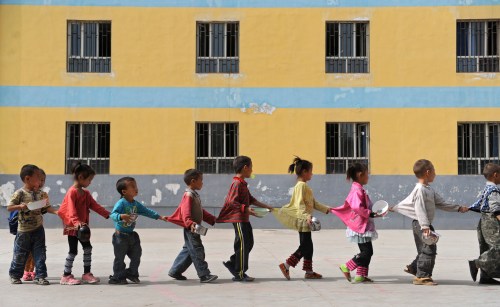 Students walk in line towards a dining hall for lunch at a primary school for children of migrant workers in Aksu