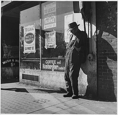 Destitute man leaning against vacant store (by Dorothea Lange, 1935)