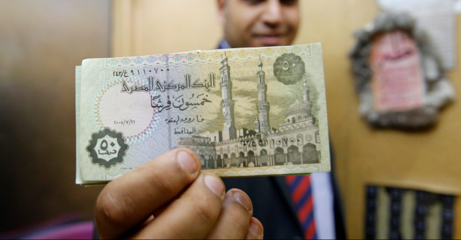 A bank employee holds up a stack of 50 piastre notes at Bank Misr in downtown Cairo, Egypt June 8, 2016. REUTERS/Amr Abdallah Dalsh - RTSGPW8