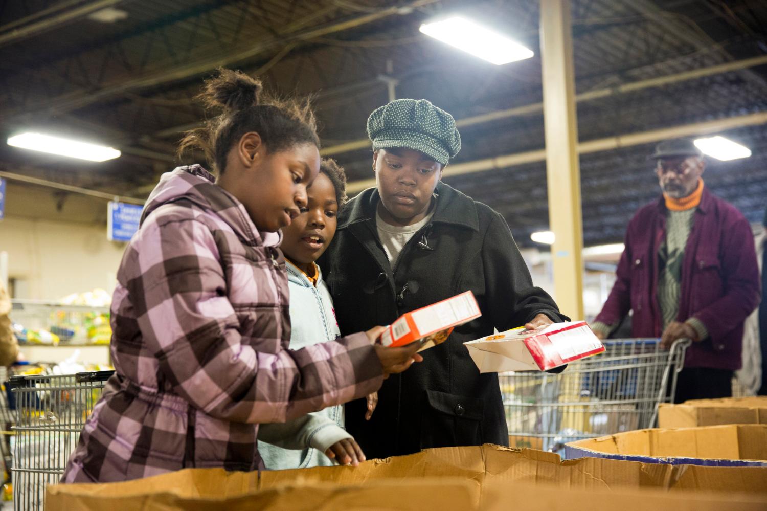 Miller compares items with her daughters at St. Vincent de Paul food pantry in Indianapolis