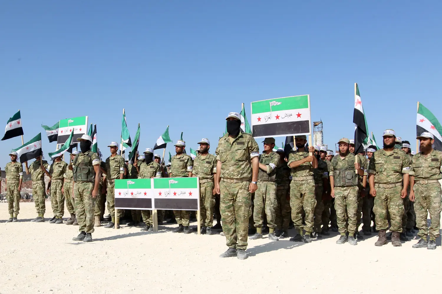 Fighters from Jaish al-Izzah, part of the Free Syrian Army, stand in attention during a military display as part of a graduation ceremony at a camp in the Hama province, Syria July 29, 2016. REUTERS/Ammar Abdullah - RTSK90N