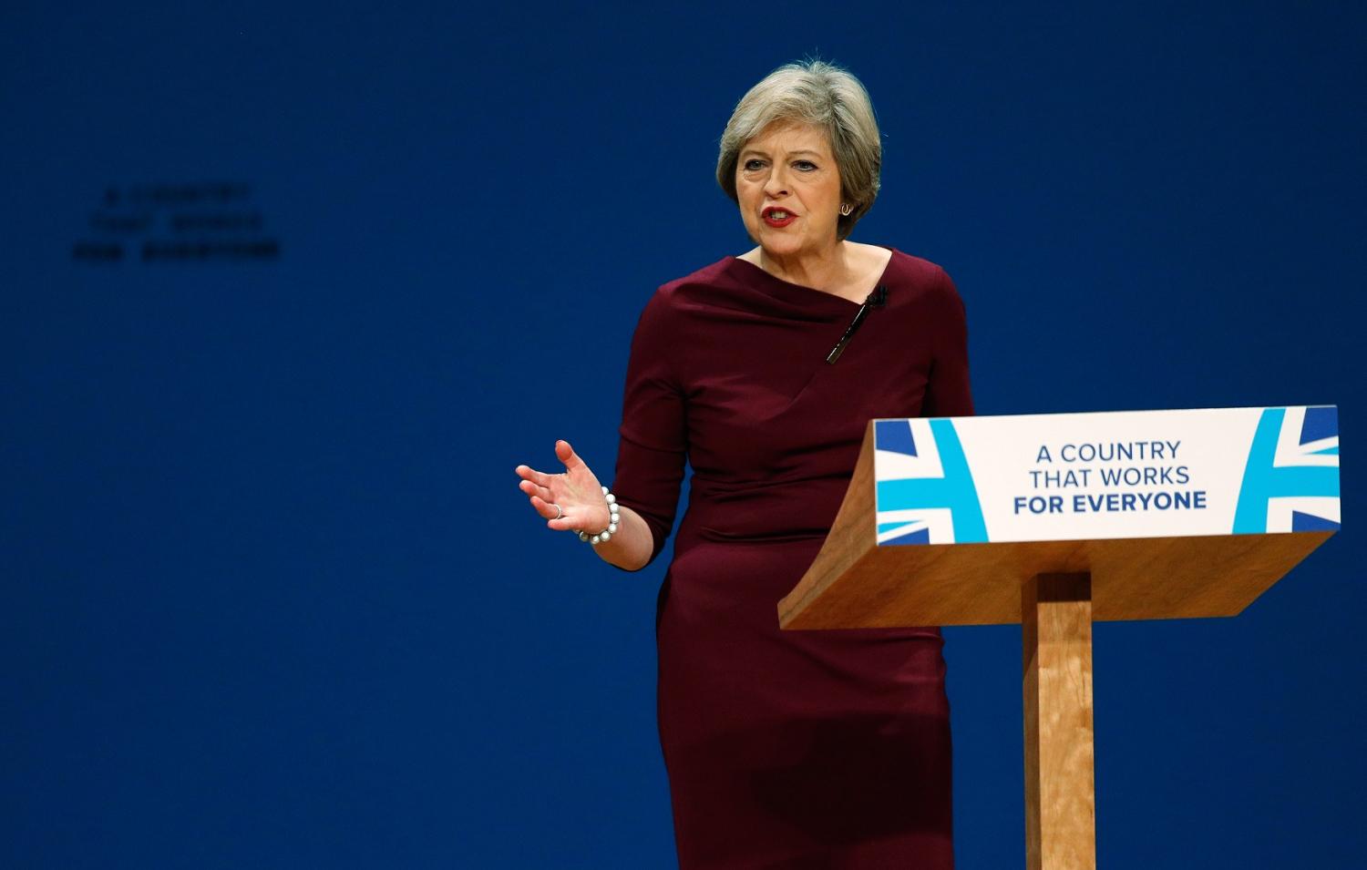 Theresa May gestures with one hand at the podium.