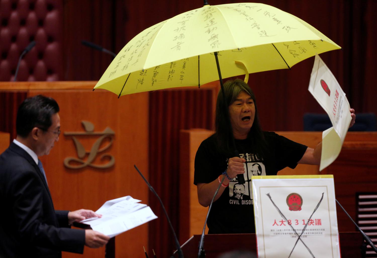 Re-elected lawmaker Leung Kwok-hung holds an umbrella while taking oath at the Legislative Council in Hong Kong, China October 12, 2016. REUTERS/Bobby Yip TPX IMAGES OF THE DAY - RTSRVA6