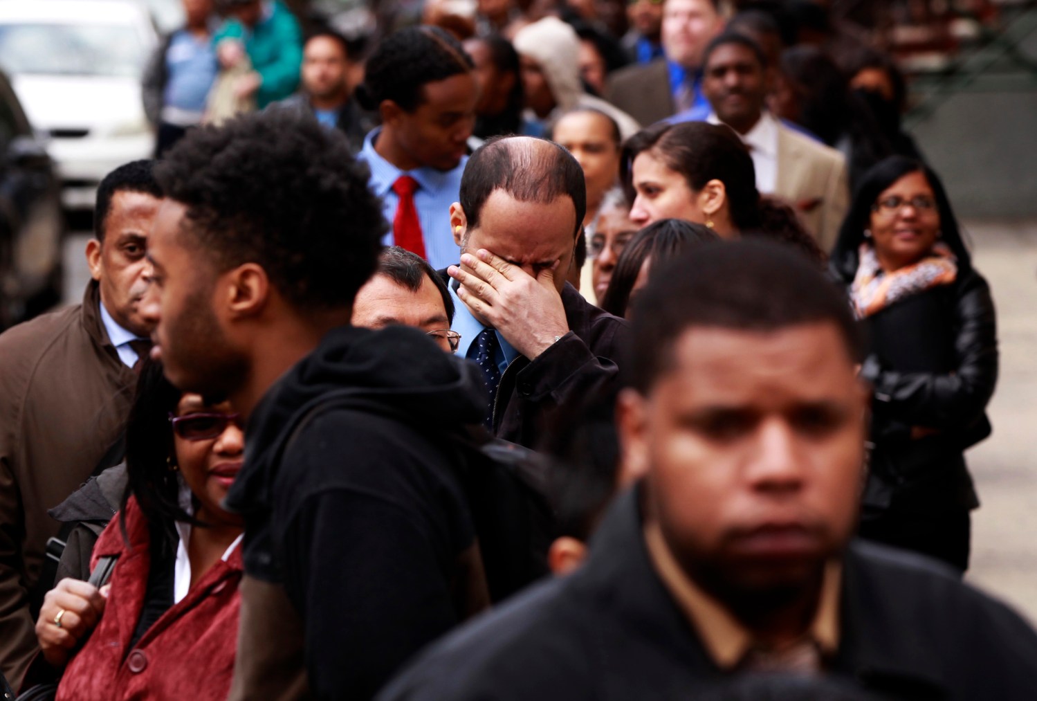 Man rubs his eyes as he waits in a line of jobseekers, to attend the Dr. Martin Luther King Jr. career fair held by the New York State department of Labor in New York