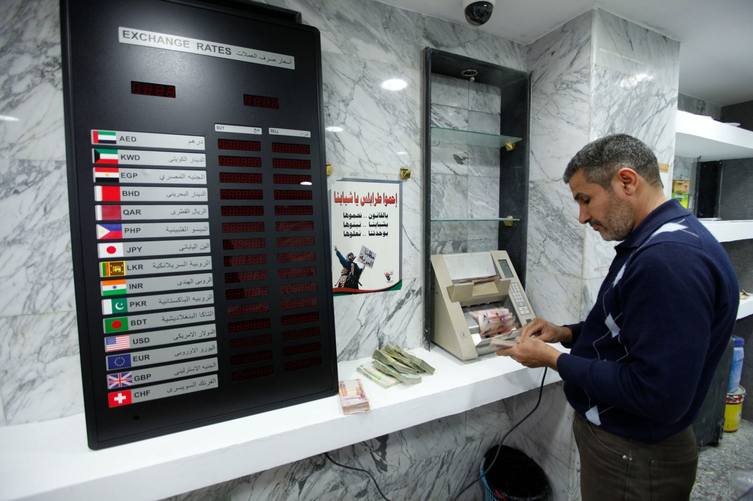 A man uses a currency counting machine to count Libyan dinar at a currency exchange office in central Tripoli March 30, 2014. Libya is burning through central bank reserves and scrapping infrastructure projects to overcome its worst budget crisis in decades after the seizure of oil installations by armed groups has reduced the government's income almost to zero. Picture taken March 30, 2014. REUTERS/Ismail Zitouny (LIBYA - Tags: POLITICS CIVIL UNREST BUSINESS) - RTR3JBYF