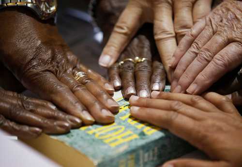 Hands of poll workers are seen on a Bible as head precinct judge Deloris Reid-Smith reads the voters oath to poll workers before opening the polls