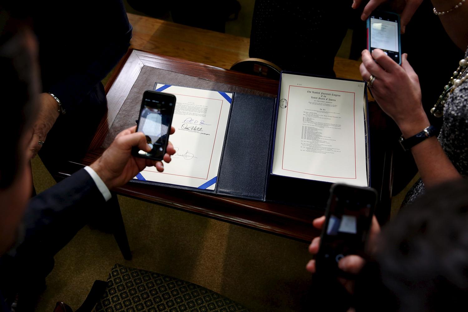 Guests take pictures of the Every Student Succeeds Act after U.S. President Barack Obama signed it into law in the Eisenhower Executive Office Building at the White House in Washington, December 10, 2015.