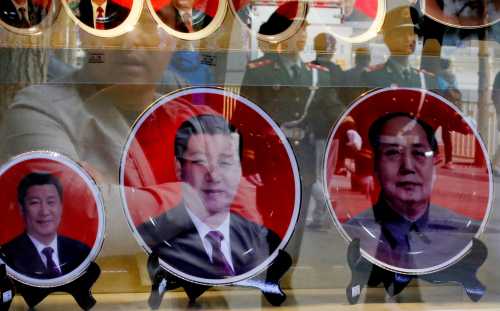 FILE PHOTO - Paramilitary policemen and pedestrians are reflected on the shop window of a shop selling souvenirs bearing the pictures of China's President Xi Jinping (L) and former leaders near the Great Hall of the People in Beijing October 23, 2014. China wrapped up the fourth plenary session of the 18th Communist Party Central Committee on Thursday in Beijing. REUTERS/Kim Kyung-Hoon/File Photo - RTX2QS1A