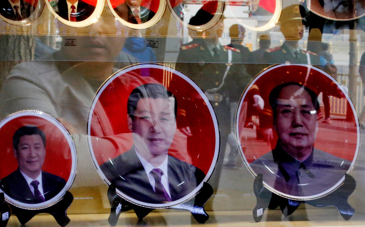 FILE PHOTO - Paramilitary policemen and pedestrians are reflected on the shop window of a shop selling souvenirs bearing the pictures of China's President Xi Jinping (L) and former leaders near the Great Hall of the People in Beijing October 23, 2014. China wrapped up the fourth plenary session of the 18th Communist Party Central Committee on Thursday in Beijing. REUTERS/Kim Kyung-Hoon/File Photo - RTX2QS1A